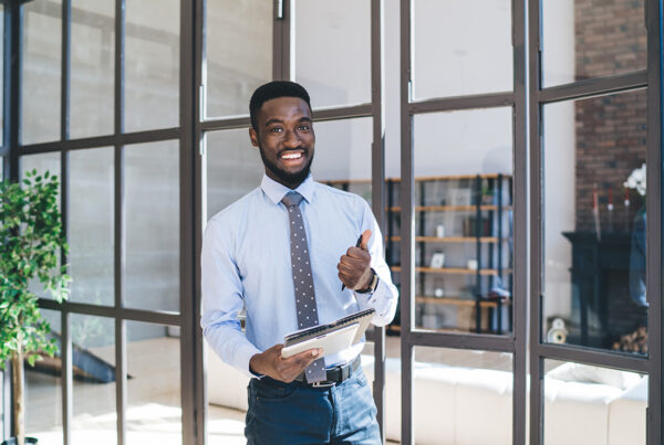 Agency Opportunity - Friendly Business Professional Standing in an Office With Modern Office Windows